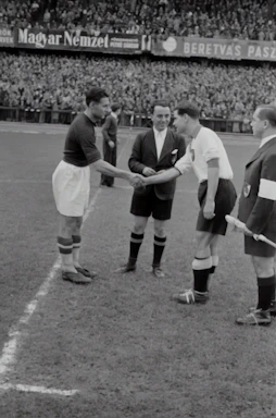 Close-up of a football agent shaking hands with a young player on a stadium background