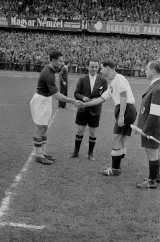 A candid moment of movie stars and politicians shaking hands before a friendly football game.