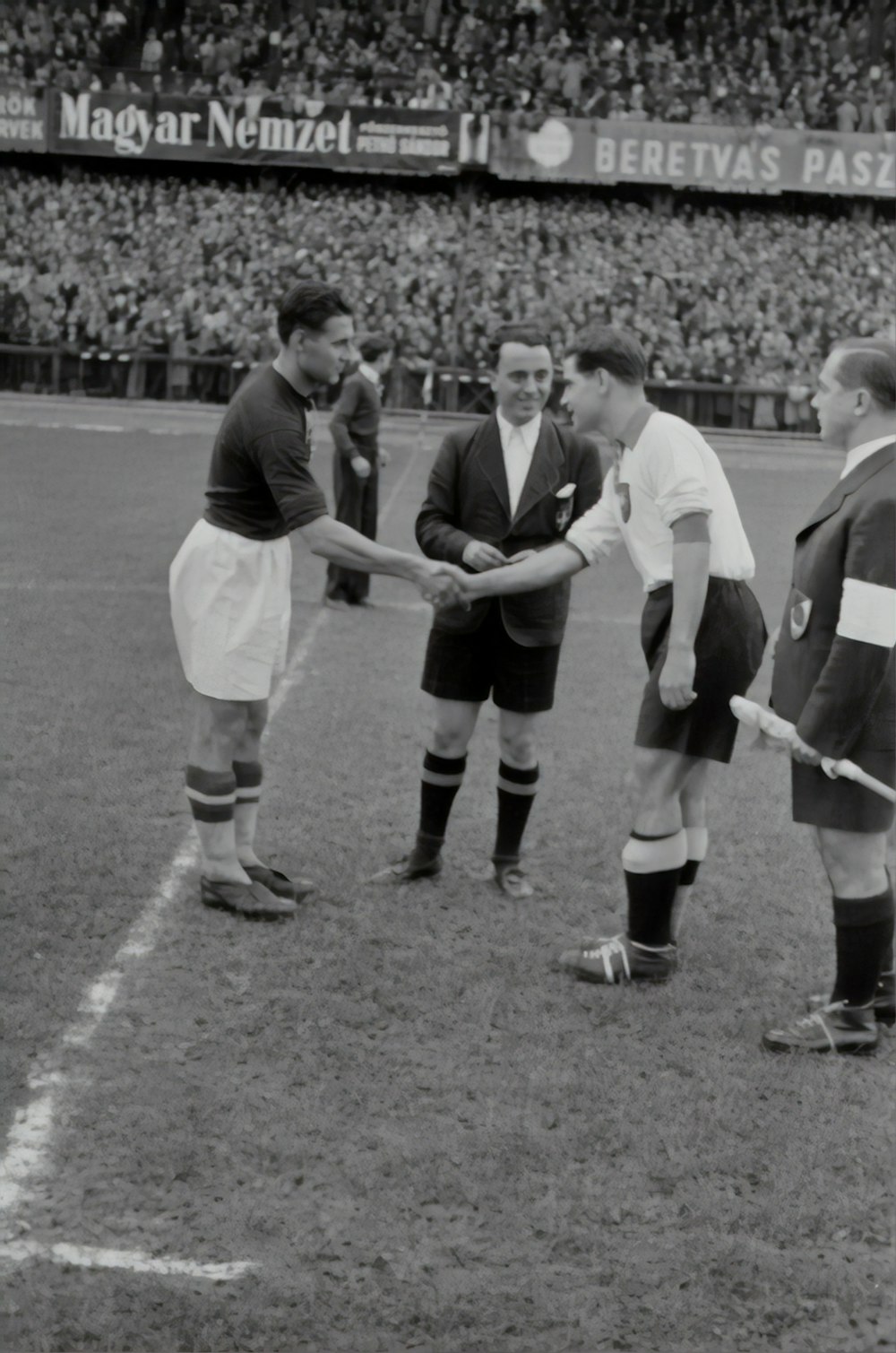 two person doing shake hands on a soccer game greyscale photograph