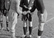 two person doing shake hands on a soccer field game