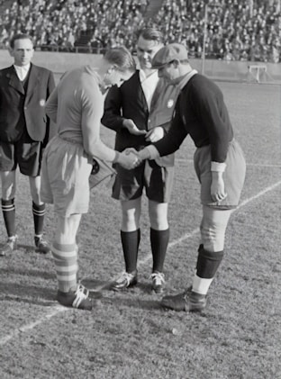 two person doing shake hands on a soccer field game