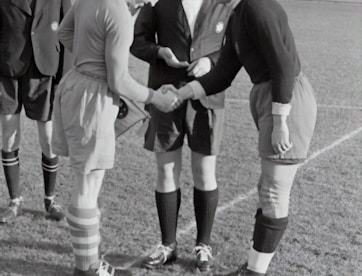 two person doing shake hands on a soccer field game