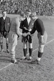 two person doing shake hands on a soccer field game