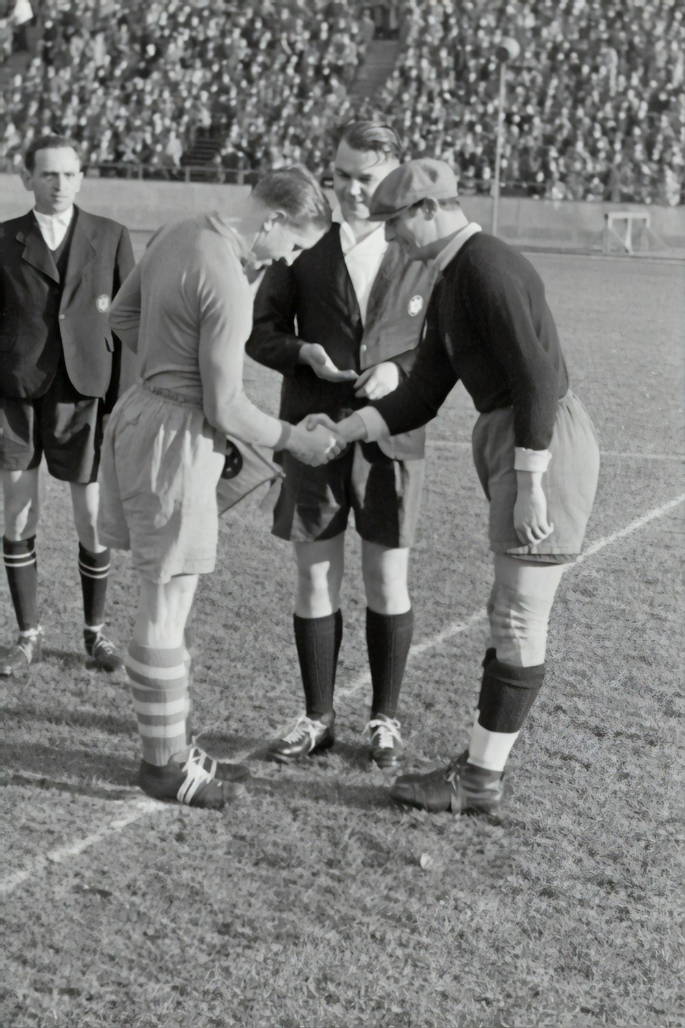 two person doing shake hands on a soccer field game