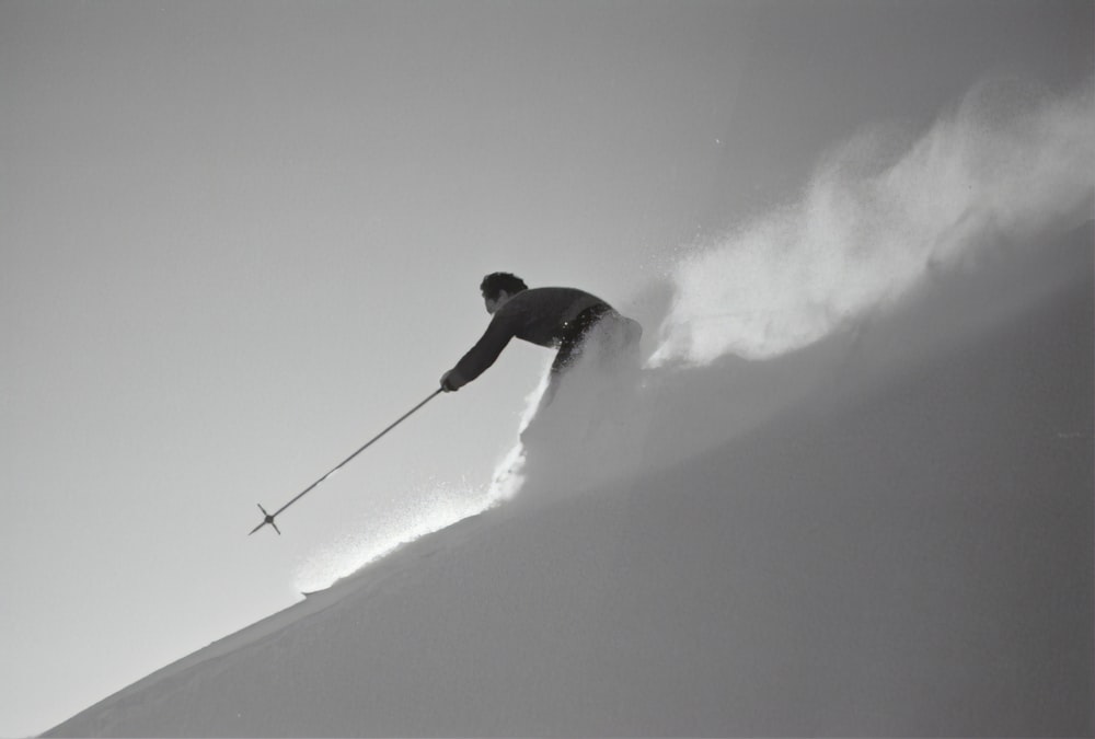 grayscale photography of man skiing on snow