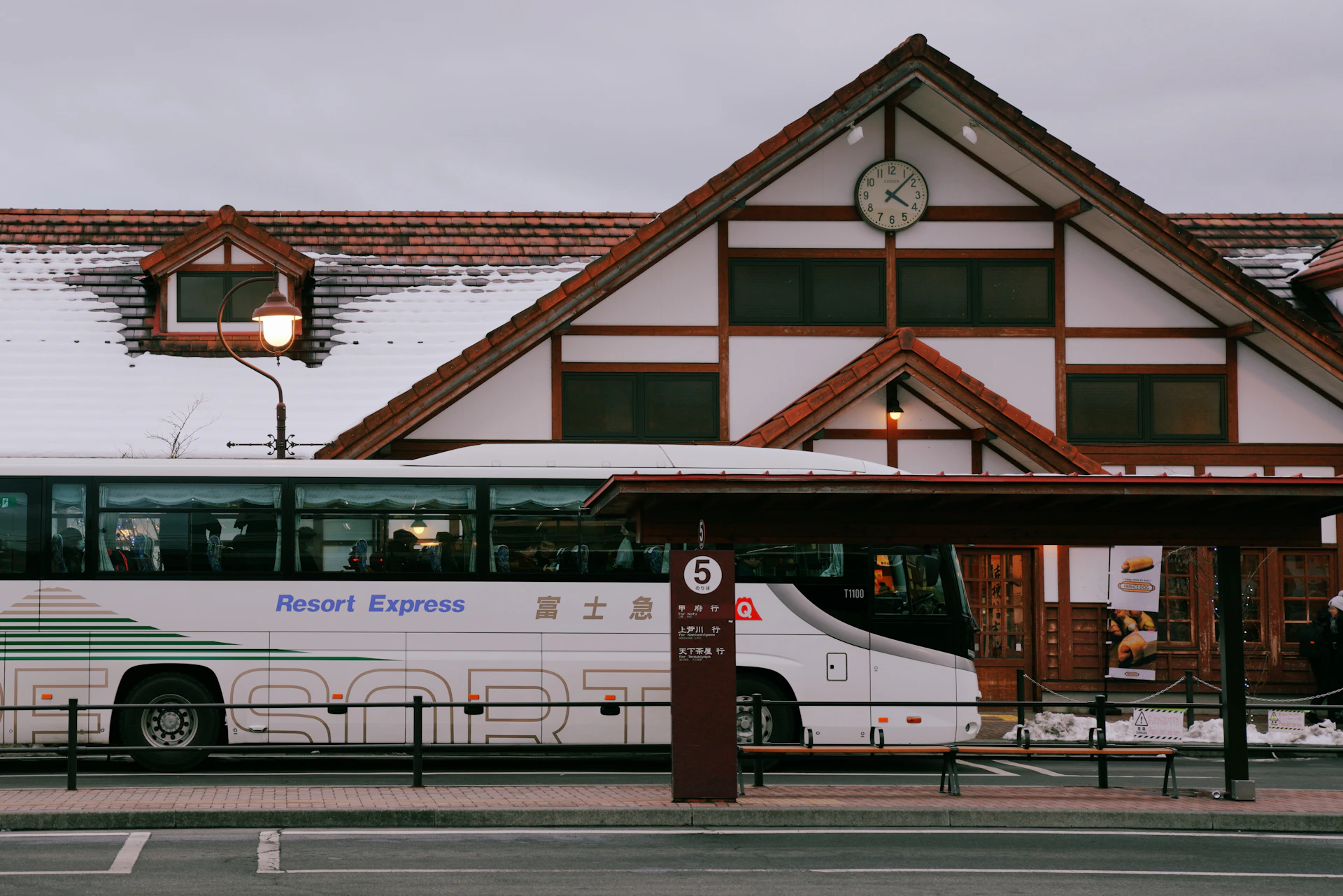A modern tour bus parked in front of a charming traditional Turkish village, ready for a comfortable transfer service.