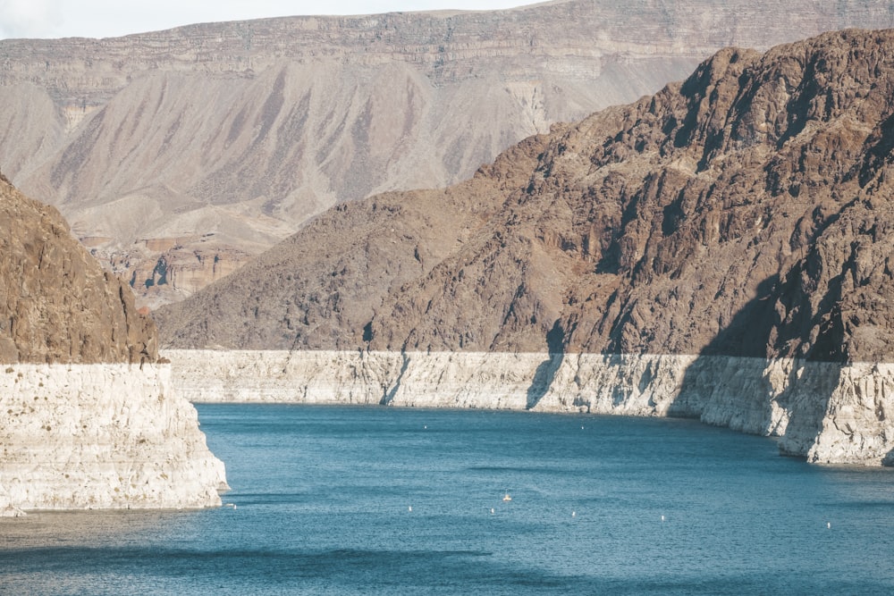 gray mountain beside body of water during daytime