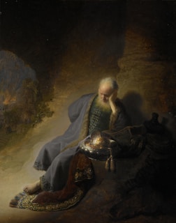 man in gray suit sitting on rock