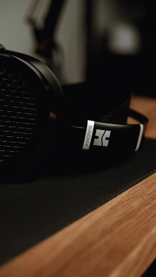 Close-up of sleek wireless headphones resting on a wooden table with soft natural light.