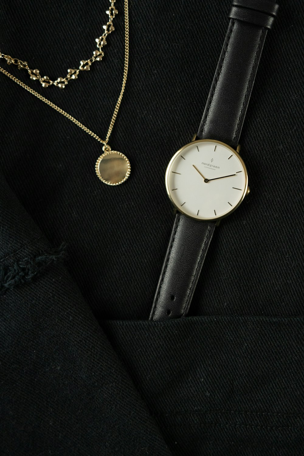 round gold-colored analog watch with black leather strap