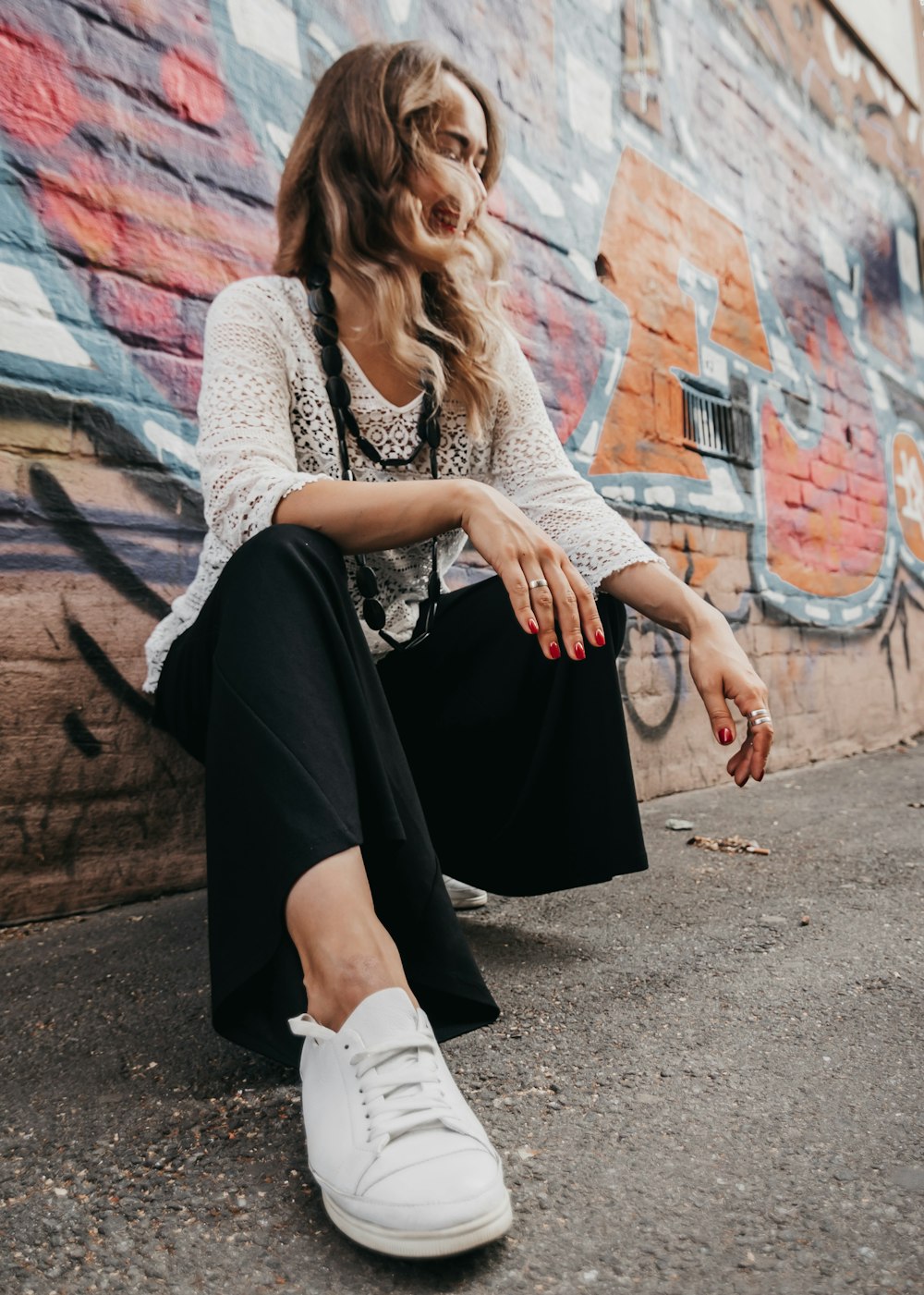 woman sitting in front of graffiti brick wall