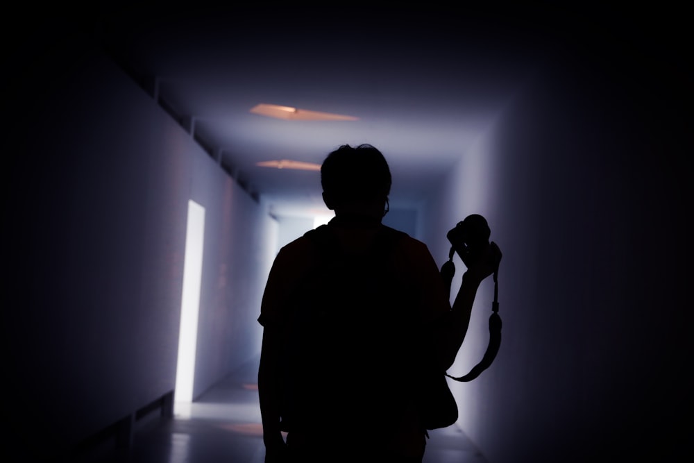 low-light photo of man walking on the hallway