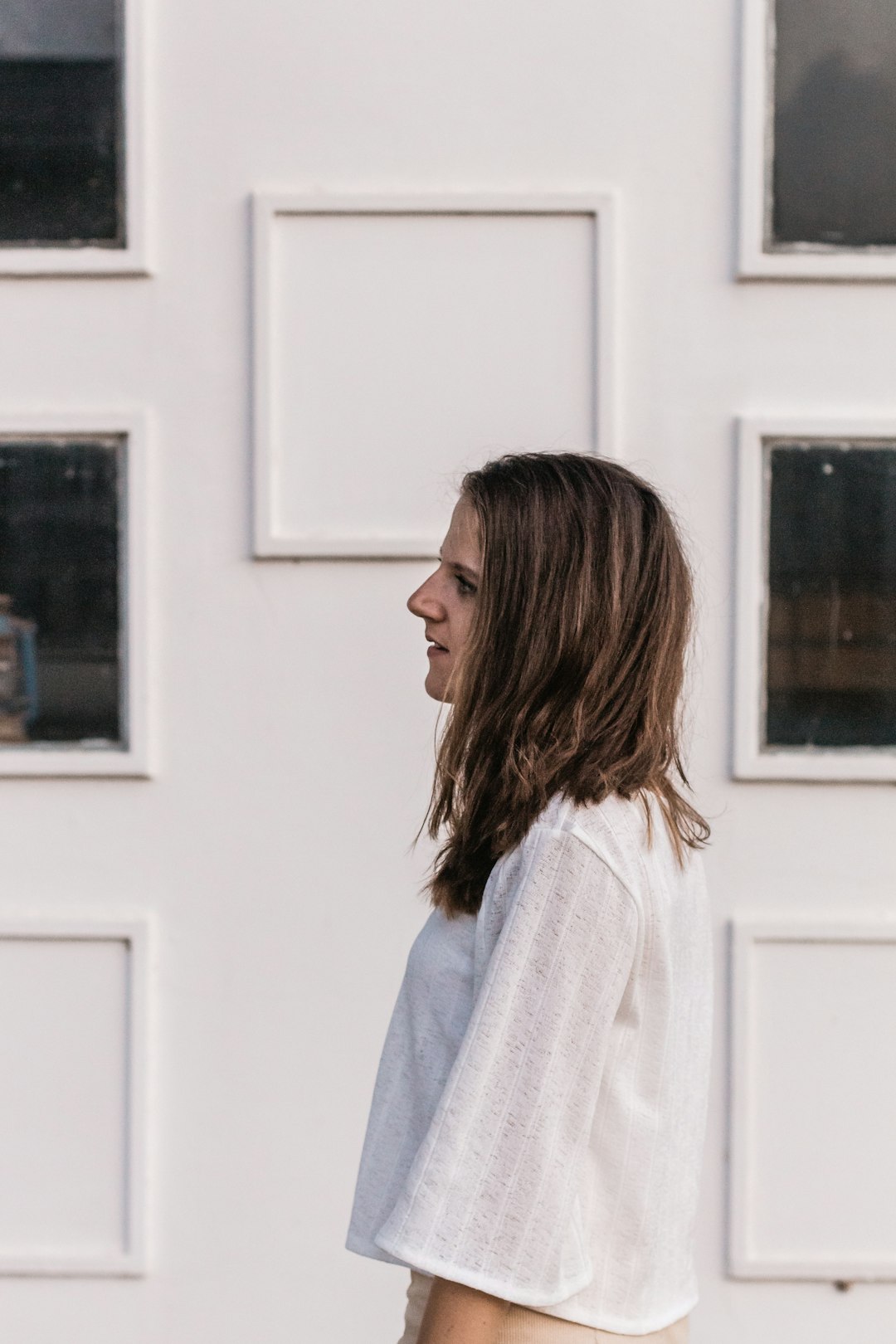 woman facing left standing in front of white wall