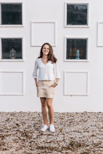 A smiling woman looking confident and motivated, standing in a bright room with soft lilac walls.