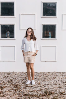 A smiling businesswoman standing next to a wall-mounted air conditioner in a bright office.
