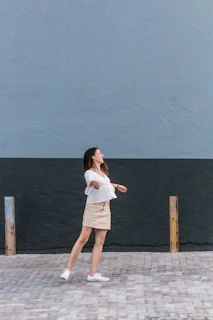 A joyful plus-size woman twirling in a stylish blouse and jeans against a minimalist background.