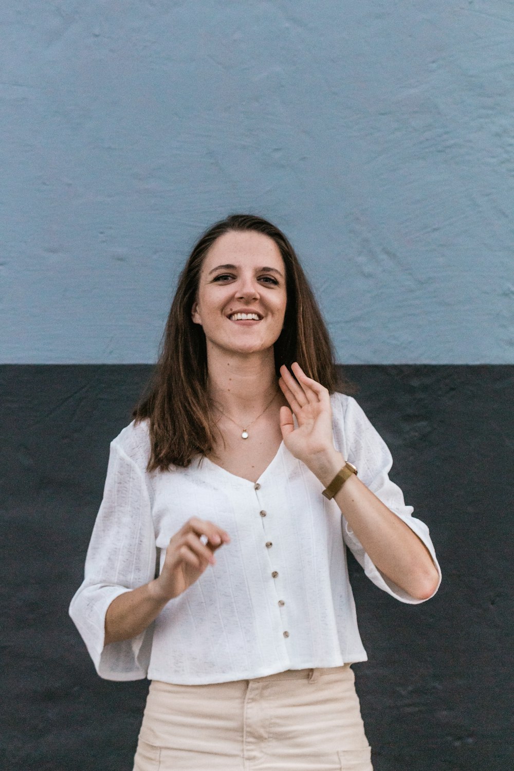 woman in white button-up long-sleeved shirt standing beside wall