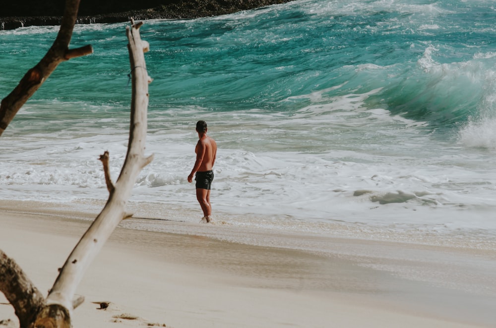 uomo in topless in piedi sulla spiaggia