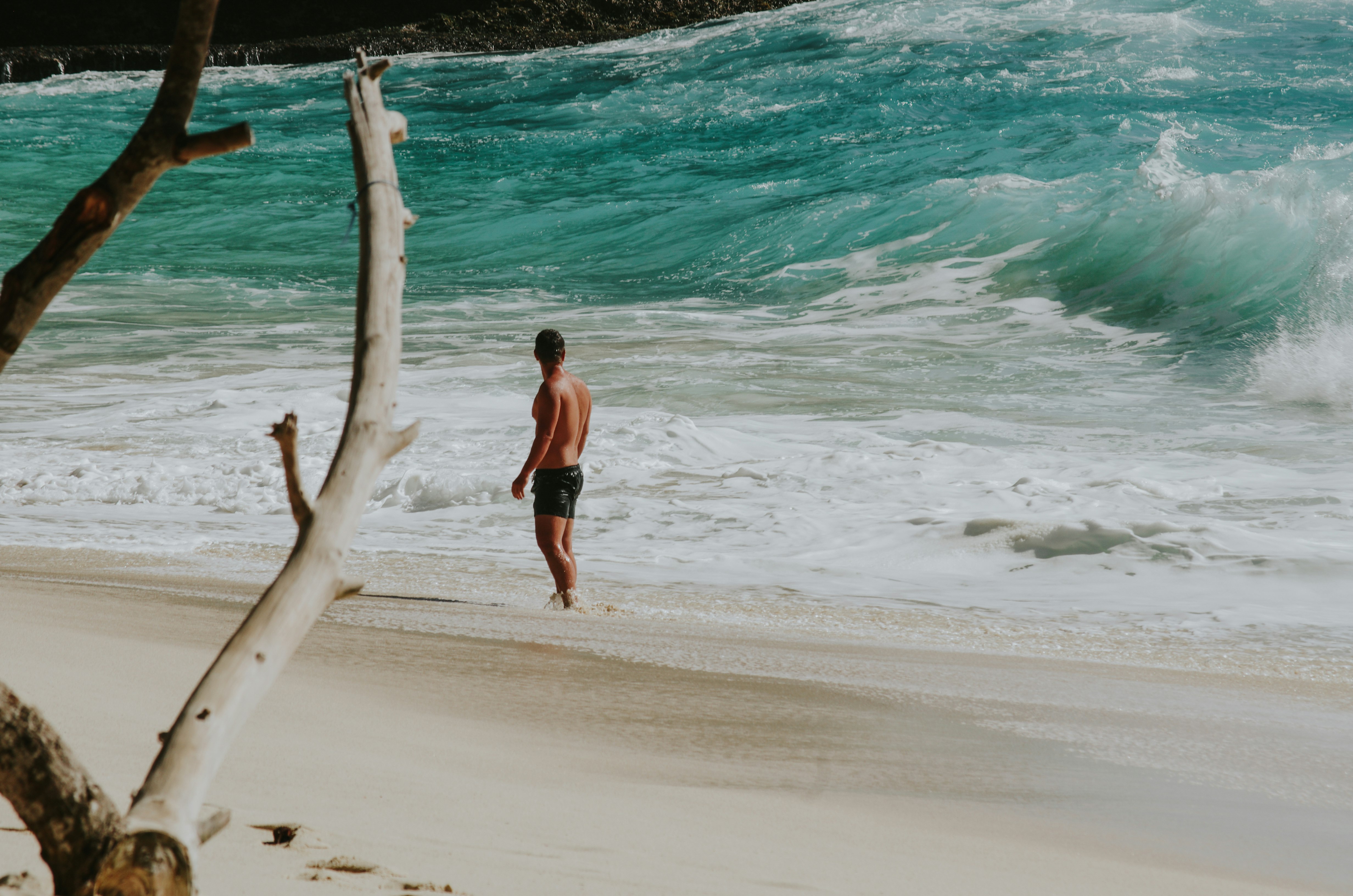 topless man standing on beach