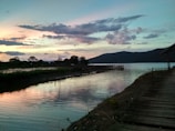 A serene view of Waduk Jatiluhur at sunset with calm waters reflecting the sky