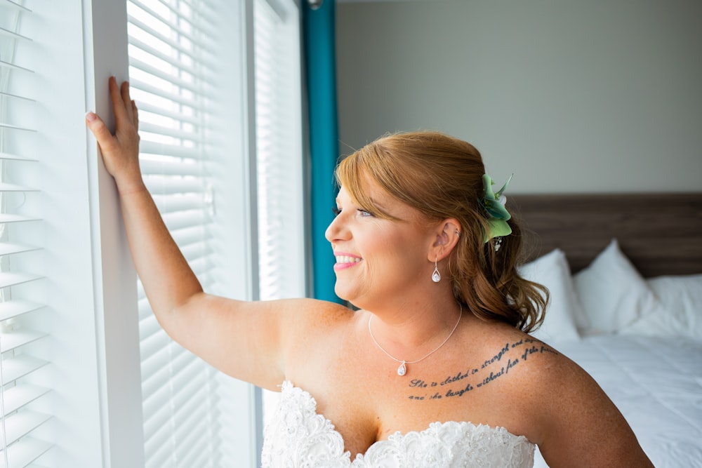 a woman in a wedding dress looking out a window