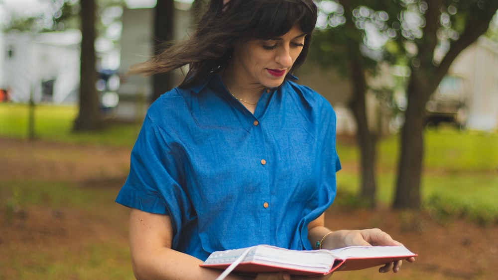 woman walking while holding and reading a book