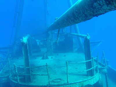 Underwater perspective of a hull with barnacles and marine life clinging to its surface.