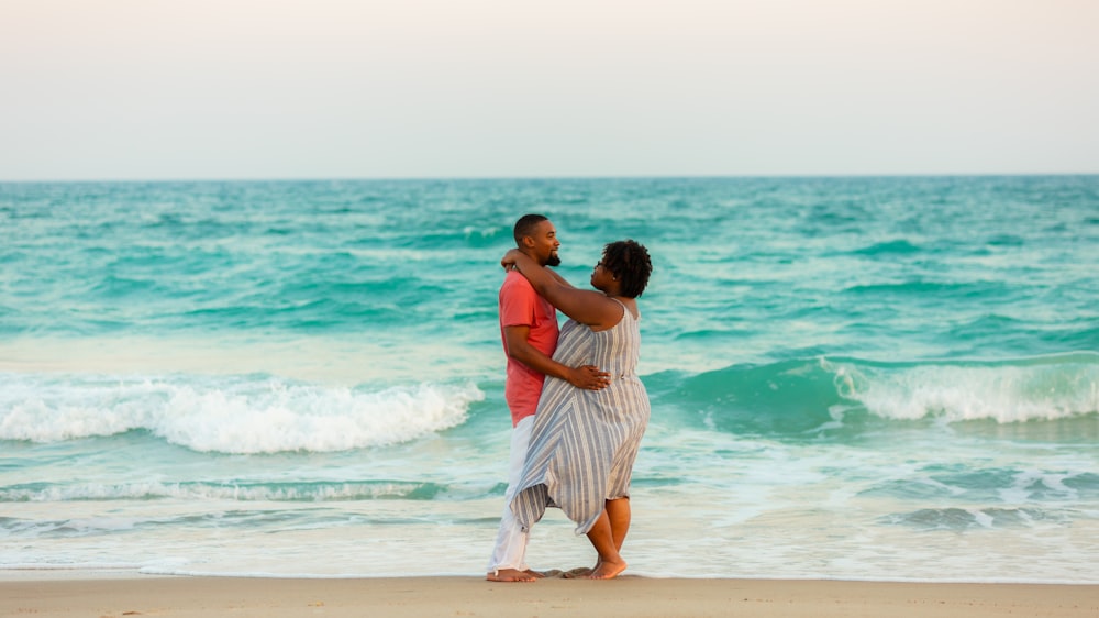 photography of man and woman hugging each other beside seashore during daytime