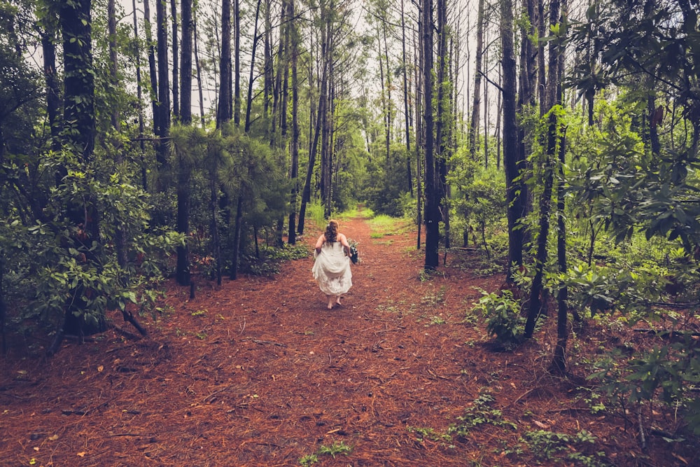 woman in white dress walking near forest during daytime