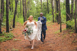 A joyful couple hiking through a sunlit forest after their wedding ceremony, capturing the spirit of adventure.