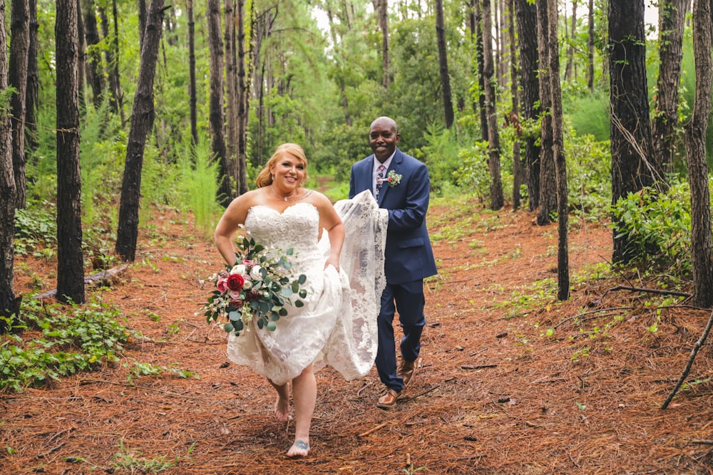 wedding couple walking in pathway surrounded by trees during daytime
