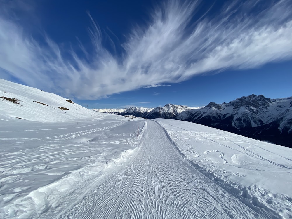 a snow covered ski slope with mountains in the background