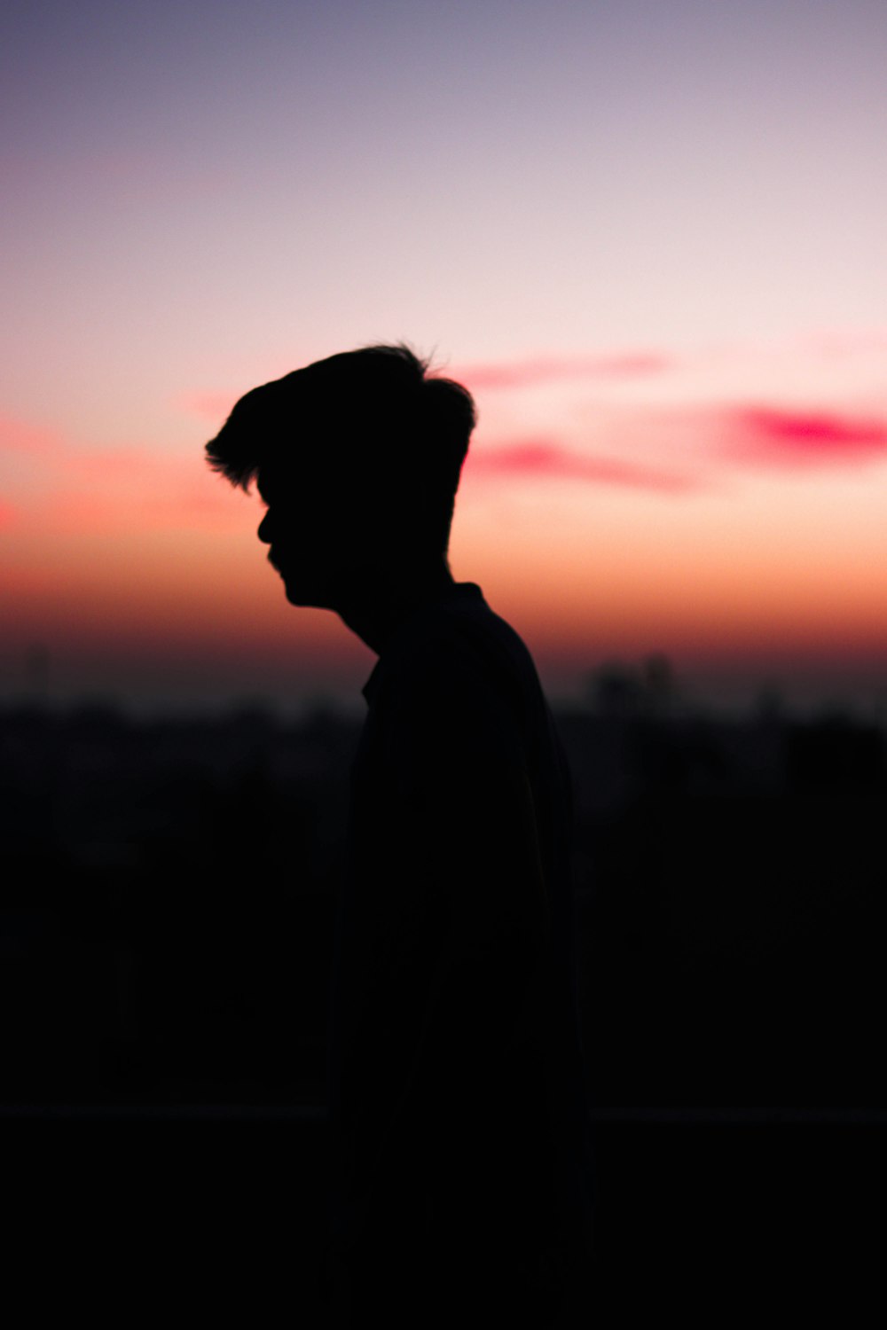 a silhouette of a man standing in front of a sunset