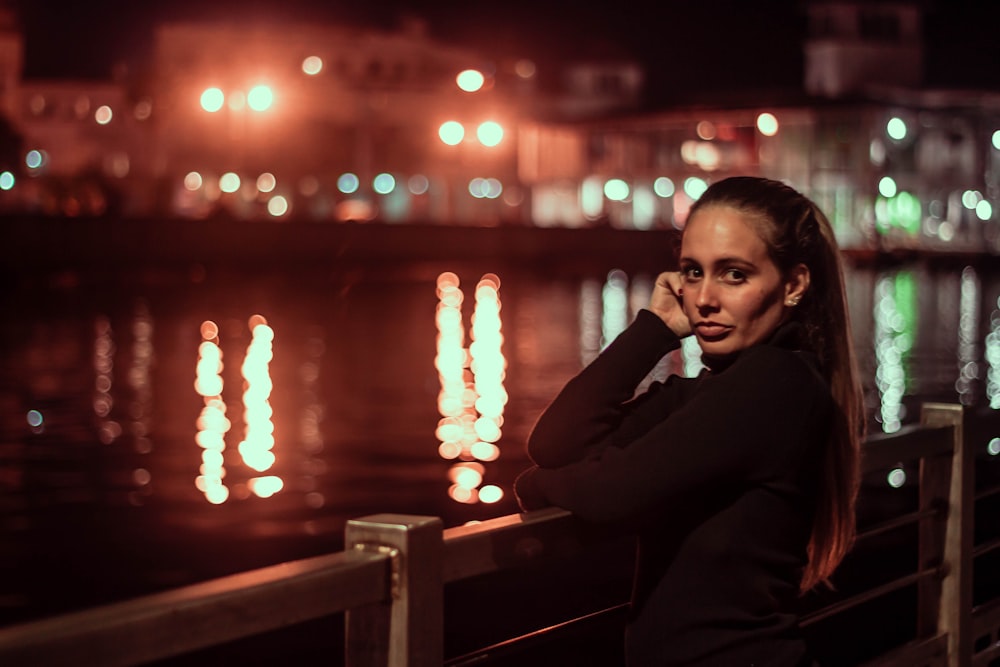 woman beside railing looking at the camera during nighttime