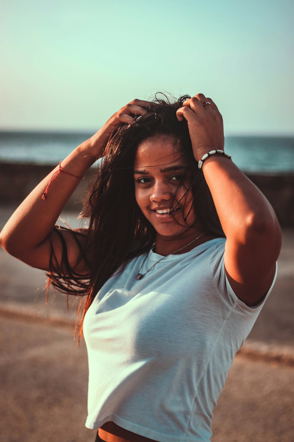 woman smiling and looking at the camera with both hands touching her hair