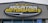 A large, rectangular business sign reads 'Mountain Motorsports' in bold letters. The text 'MOUNTAIN' is white, while 'MOTORSPORTS' is yellow, both set against a dark background. Above the text, there is an outline of mountain peaks in yellow.