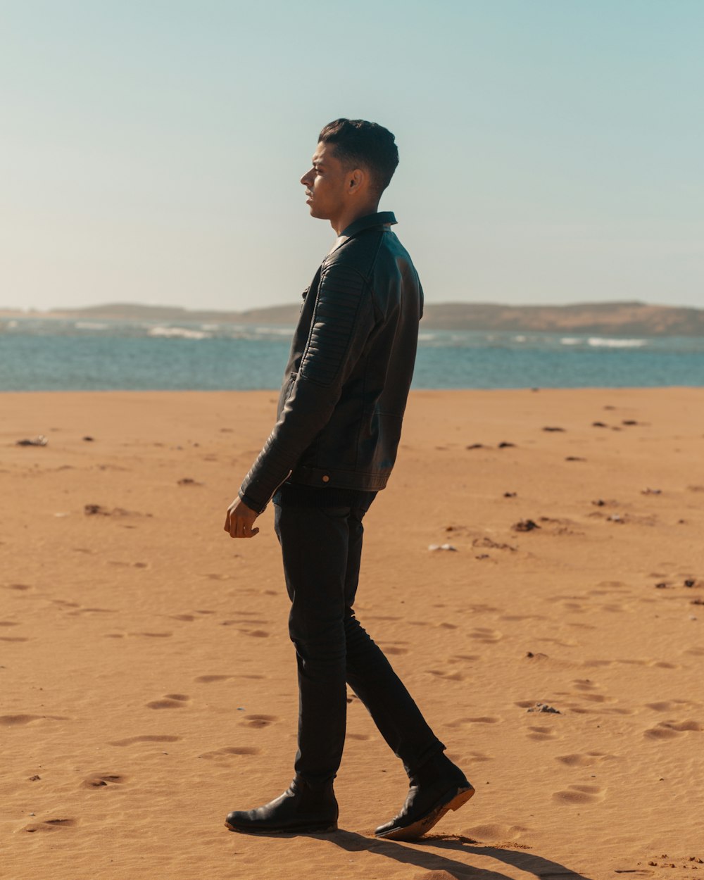 man walking on sand seashore during daytime