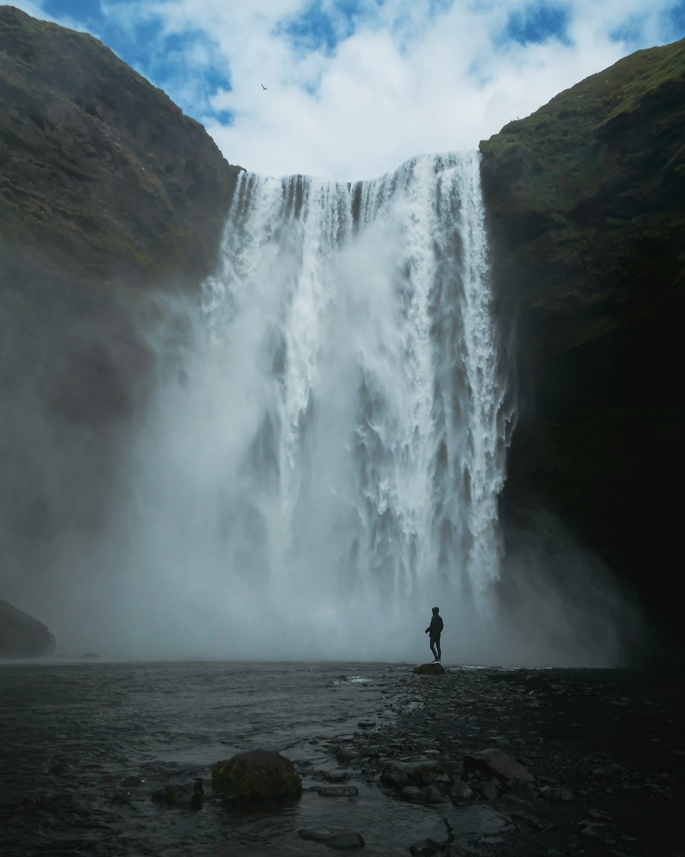 man standing near waterfalls during daytime