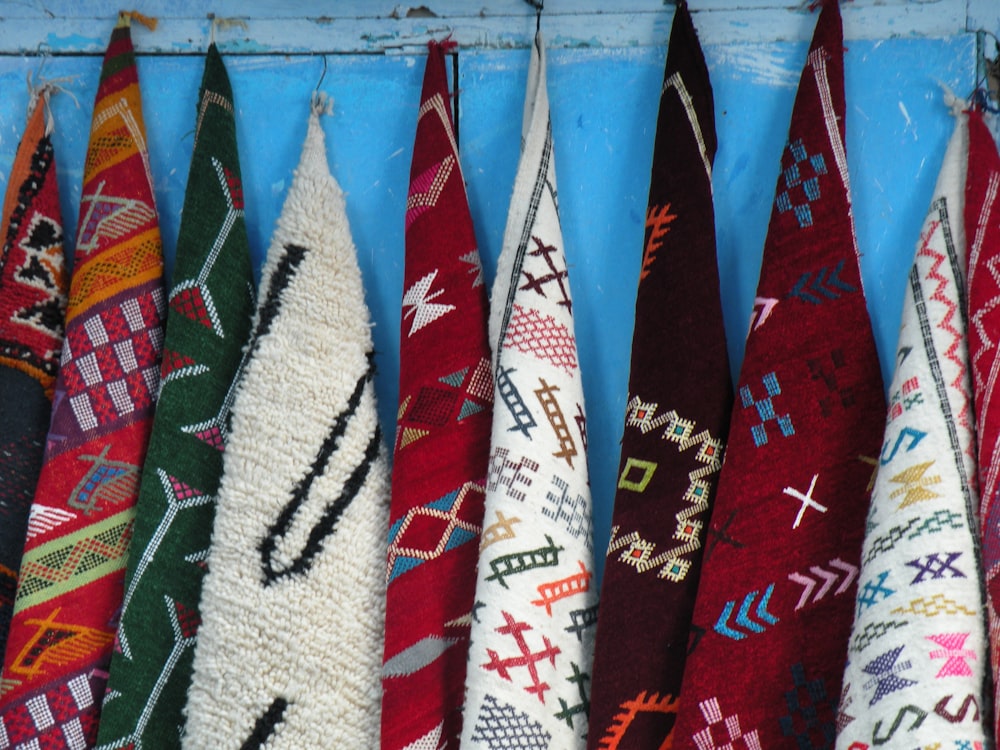 assorted-colored tribal towels hanging on blue wall