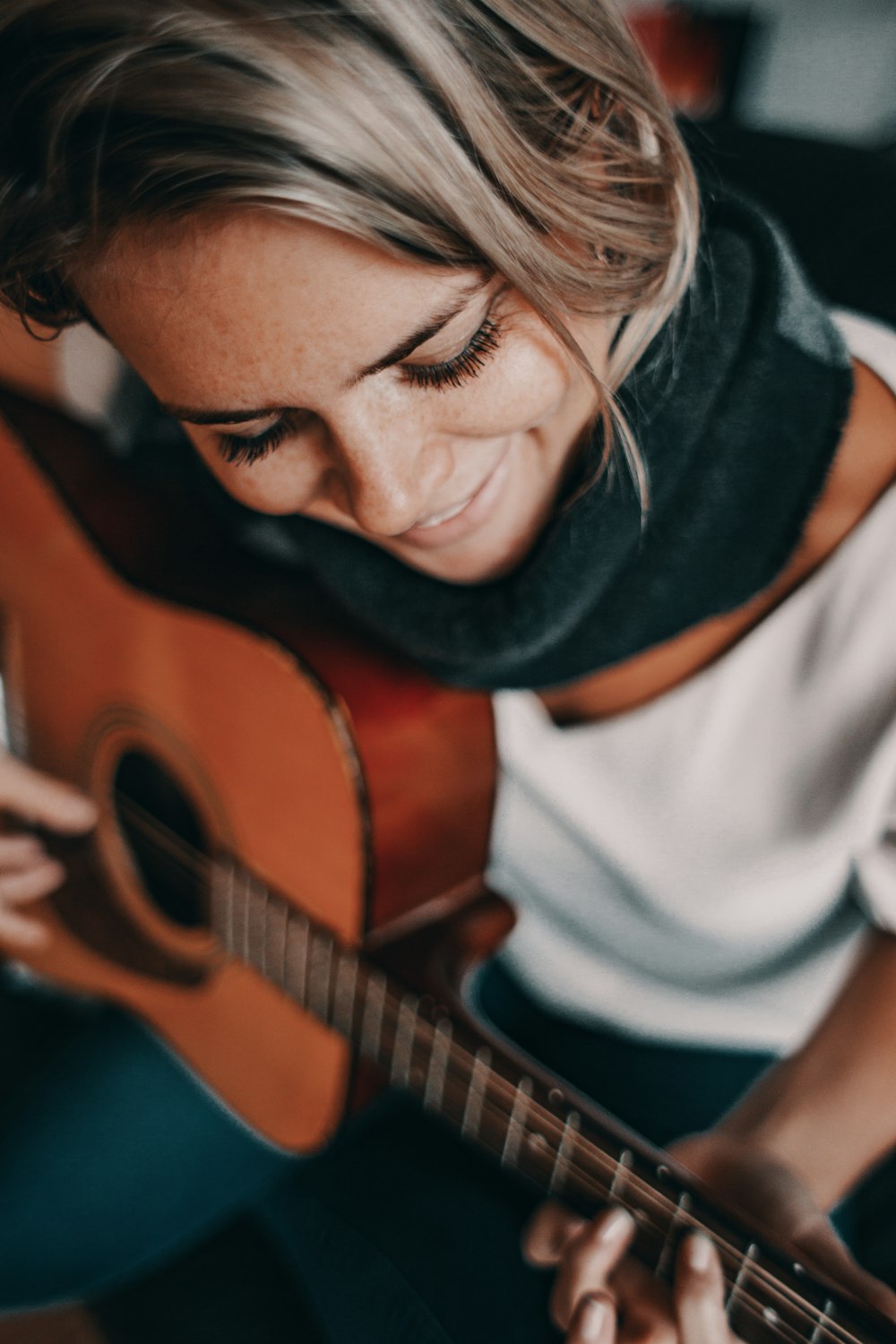 어쿠스틱 기타를 연주하는 흰색 상의의 여자