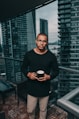 man in black crew-neck sweater standing beside glass curtain