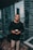 man in black crew-neck sweater standing beside glass curtain