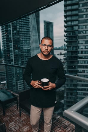 man in black crew-neck sweater standing beside glass curtain