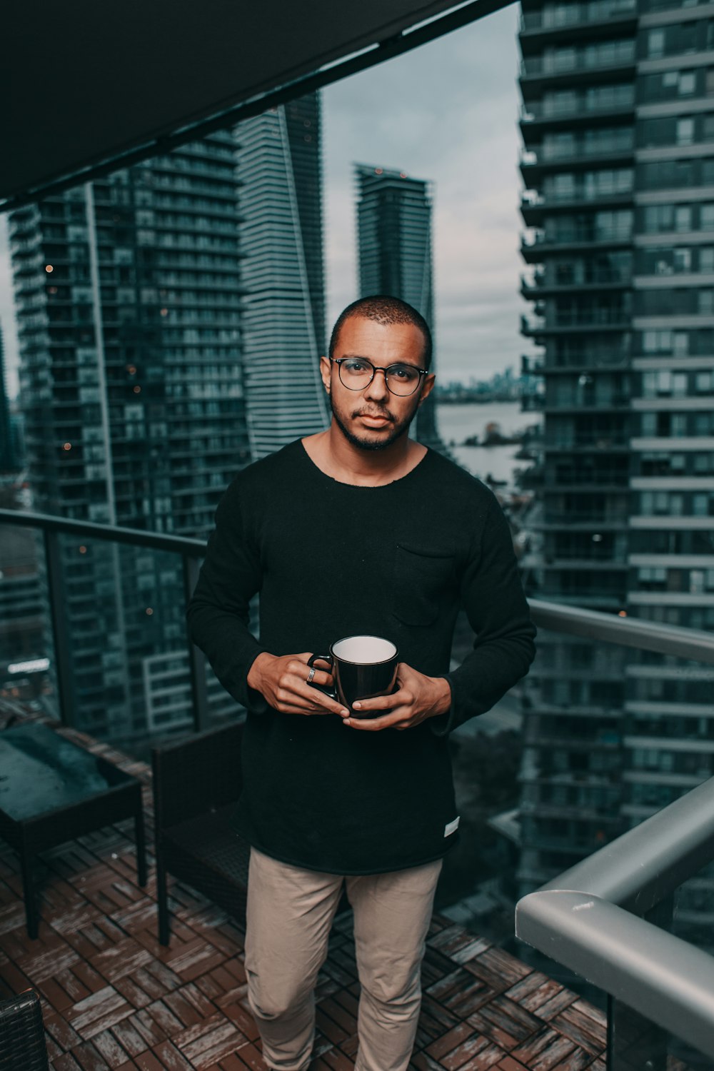 man in black crew-neck sweater standing beside glass curtain