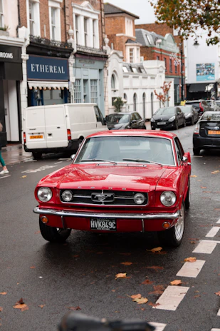 The classic Ford parked on a cobblestone street with autumn leaves scattered around.