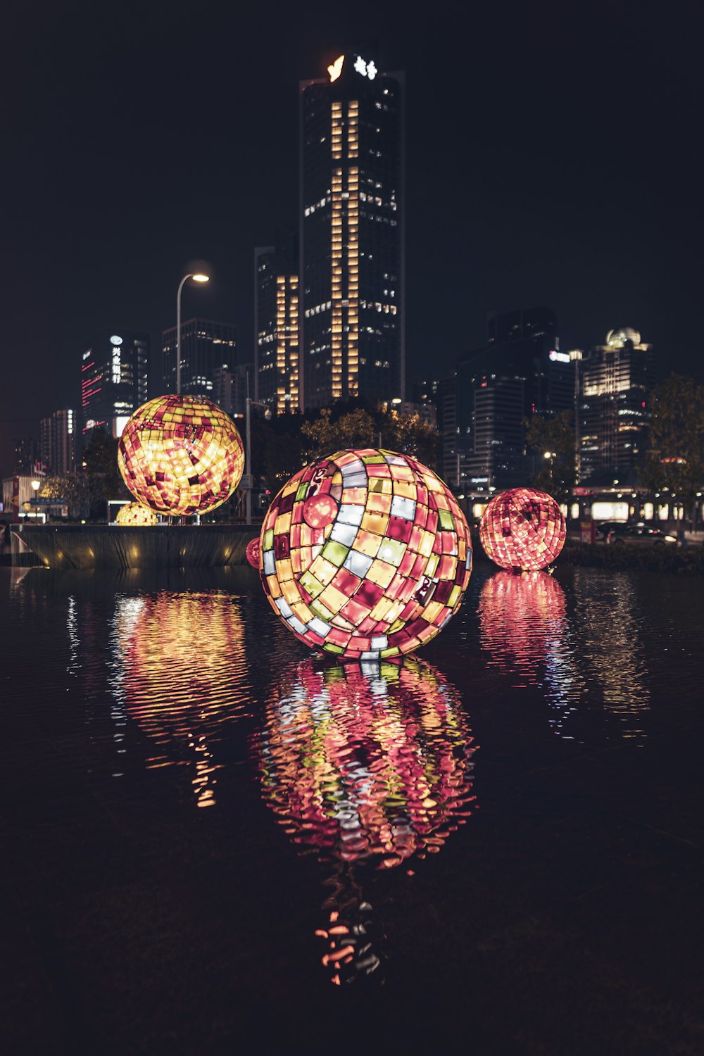 decorative balls with lights floating on body of water at the city during nighttime