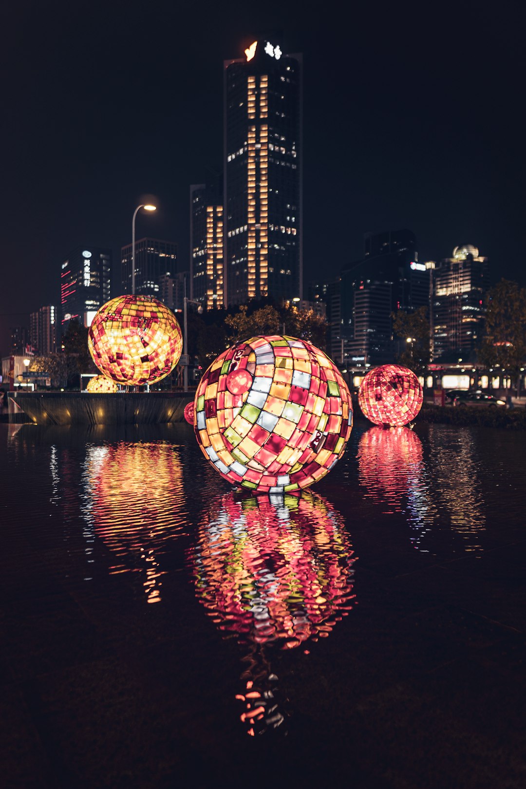 decorative balls with lights floating on body of water at the city during nighttime