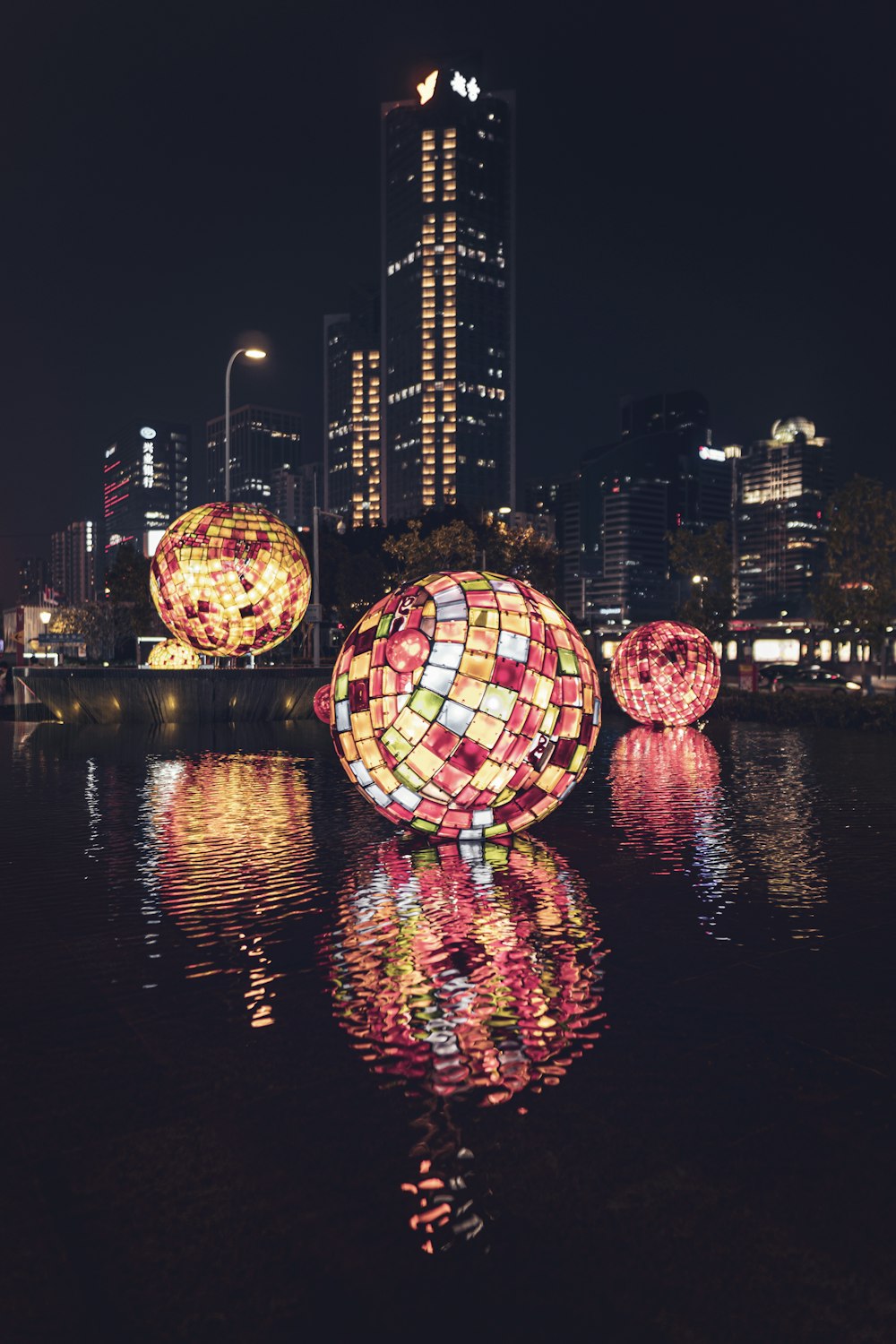 Bolas decorativas con luces flotando en el cuerpo de agua en la ciudad durante la noche