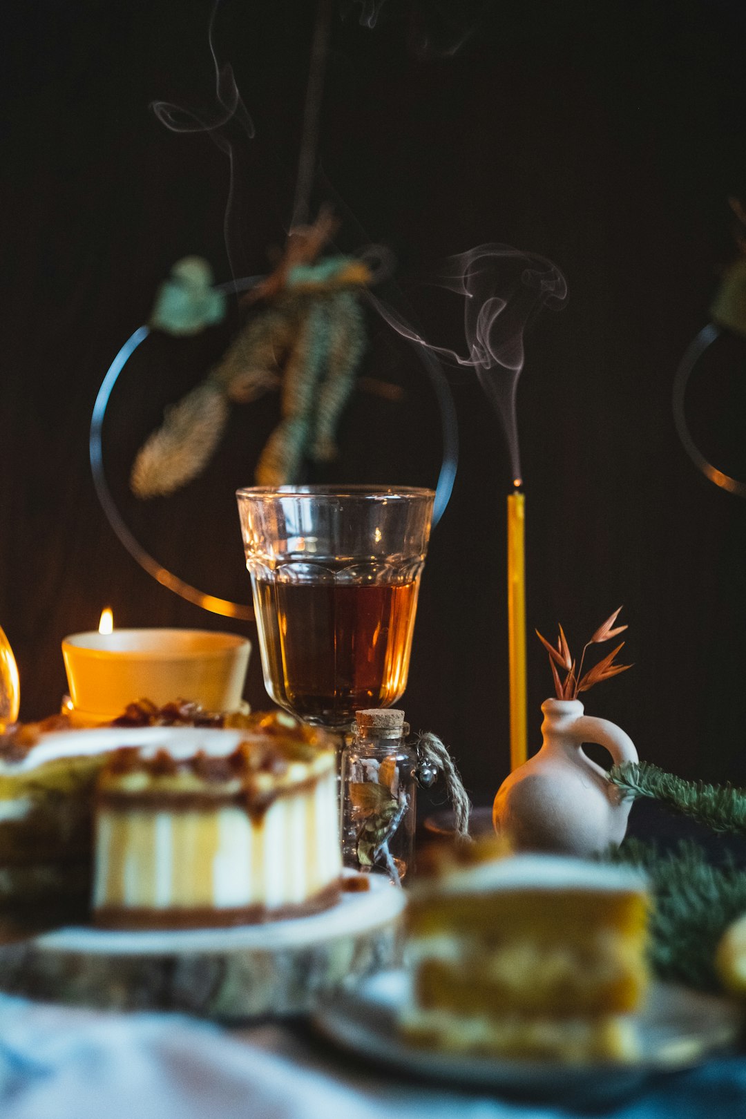 yellow candlestick near glass of wine, sliced cake, and white ceramic jar