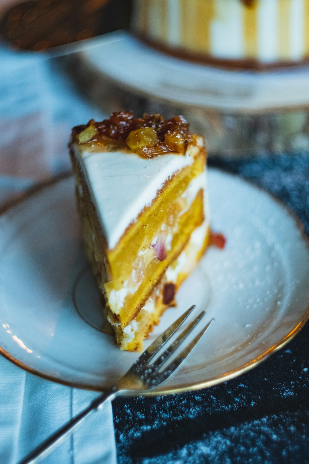 sliced cake with toppings near fork on a white and gold trim ceramic plate